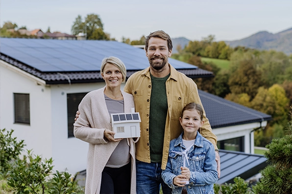 Familie vor einem modernen Haus mit Photovoltaikanlage, symbolisiert nachhaltige Energie